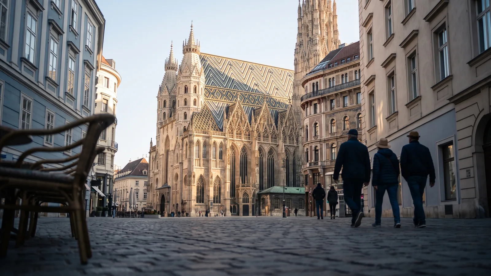 Der gotische Südturm des Stephansdoms über den Dächern und kopfsteingepflasterten Gassen der Wiener Innenstadt im warmen Spätsommerlicht.