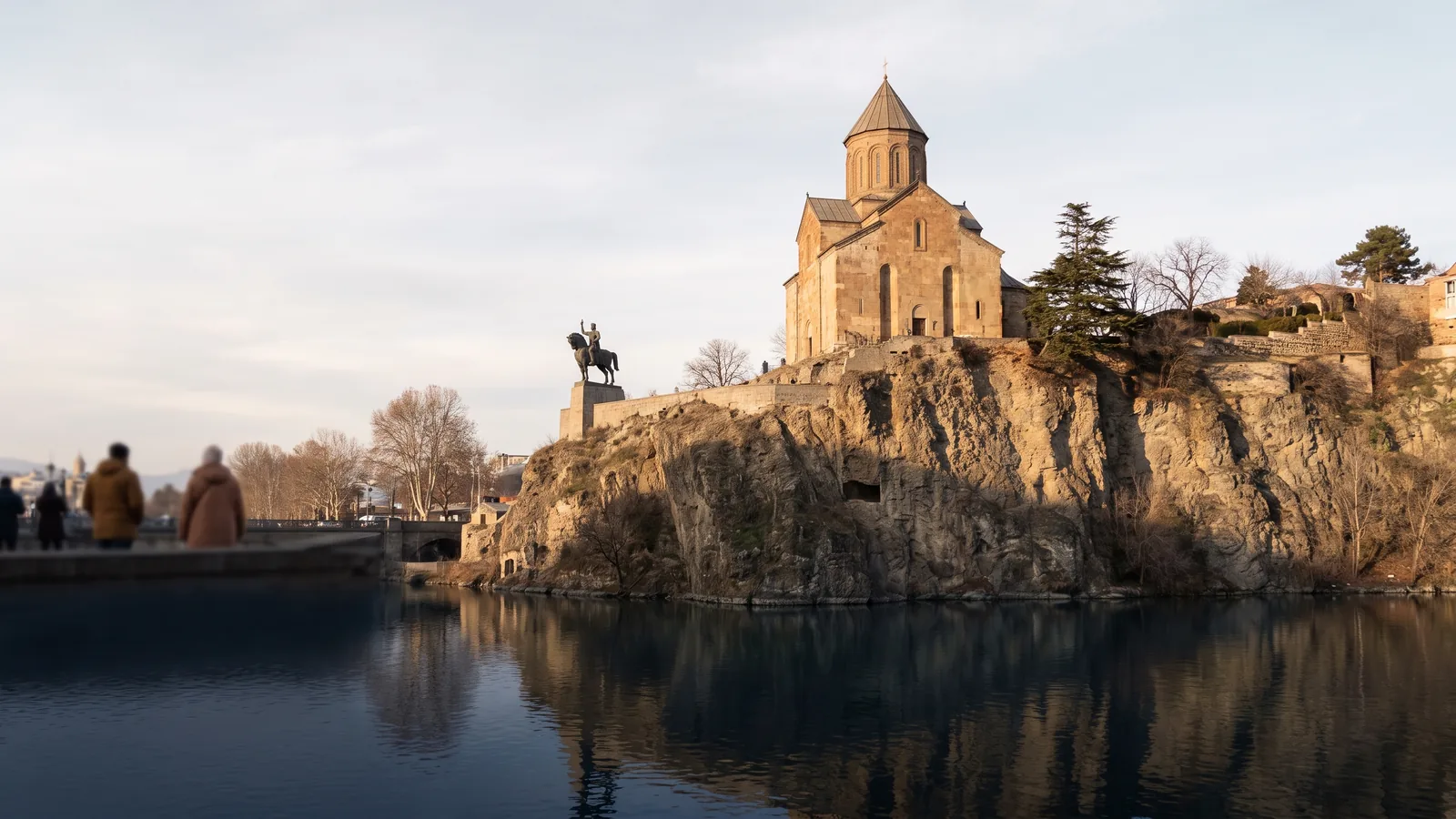 Die historische Metechi Kirche auf einem steilen Felsplateau über dem Flussufer im kühlen Winterlicht von Tiflis.