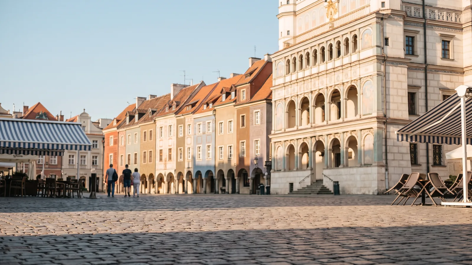 Farbenfrohe historische Kaufmannshäuser mit Bogengängen und das Renaissance Rathaus am sonnigen Alten Markt in Posen.