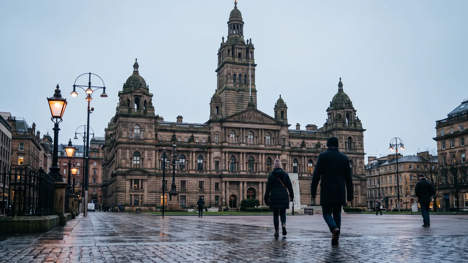 Die viktorianischen City Chambers am George Square in Glasgow unter einem kühlen winterlichen Himmel mit feuchten Steinplatten.