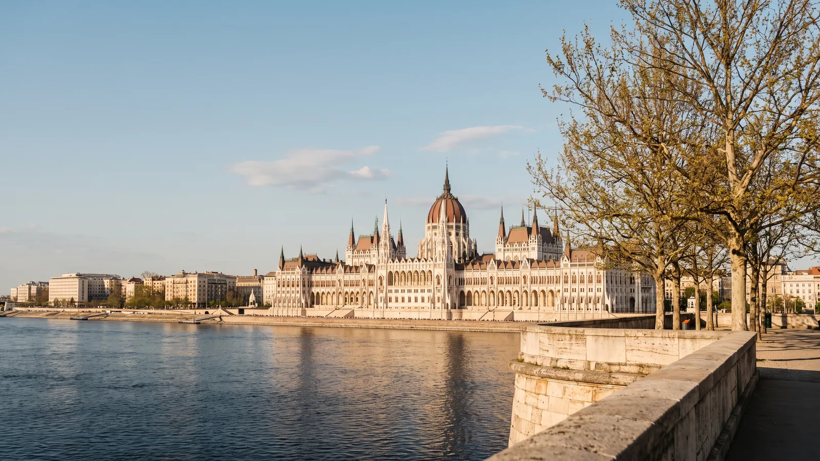 Blick über die ruhige Donau auf das neugotische Parlamentsgebäude in Budapest im milden Licht eines Frühlingsnachmittags.
