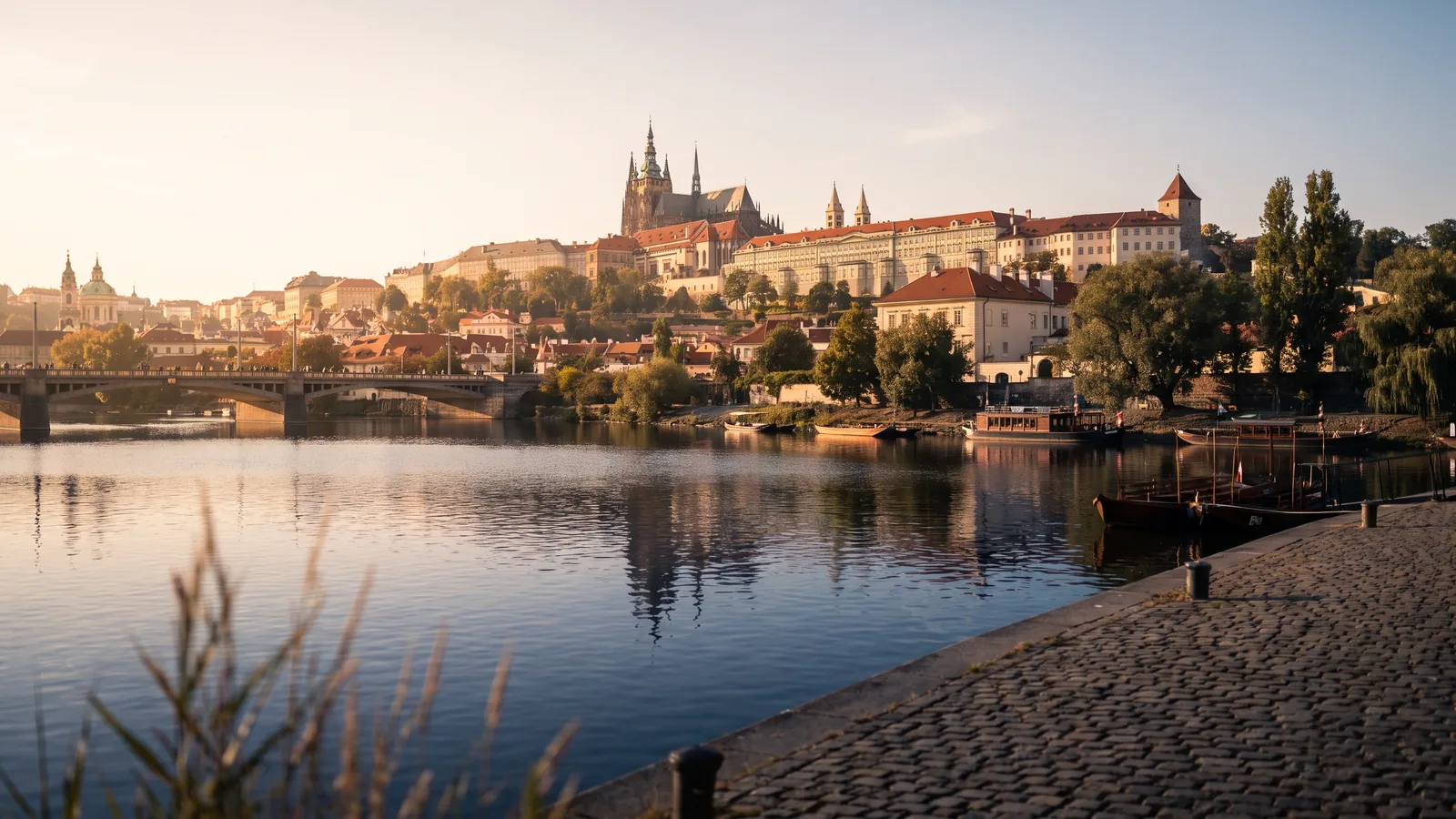 Blick über die ruhige Moldau auf die Prager Burg und den Veitsdom im warmen Licht des Spätsommers.