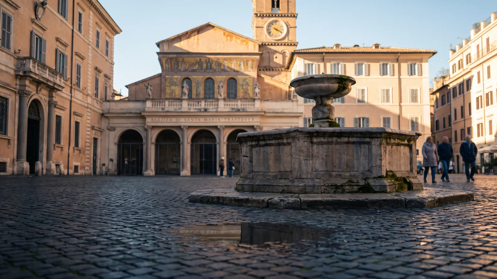 Der steinerne Brunnen und die Basilika auf der Piazza di Santa Maria in Trastevere im winterlichen Nachmittagslicht.